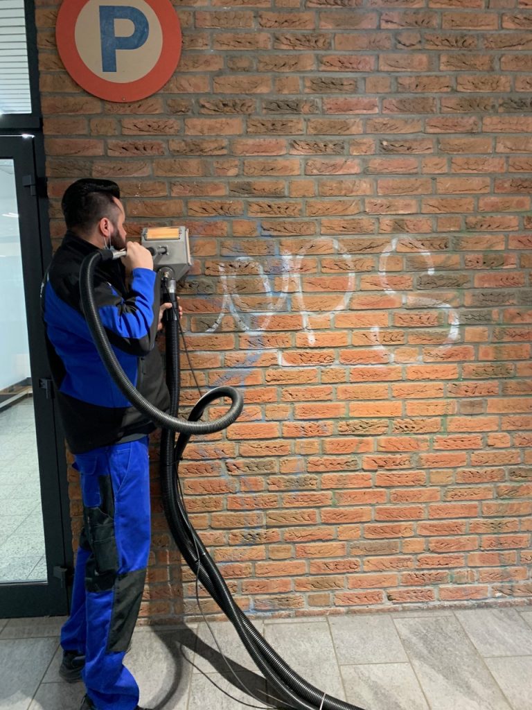 Mitarbeiter bei der Graffitientfernung an einer Hauswand
