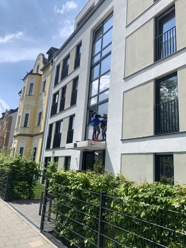 Hausfront mit sauberer Fassade und grüner Hecke