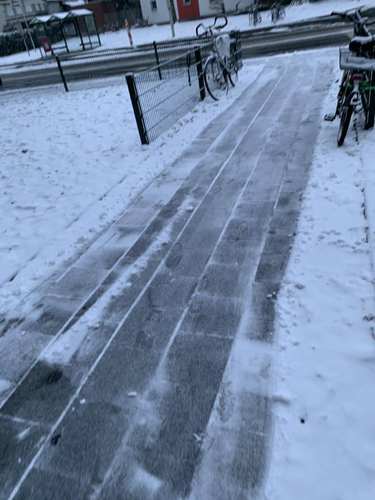 Fußweg nach Winterdienst bei Dämmerung mit abgestellten Fahrrädern
