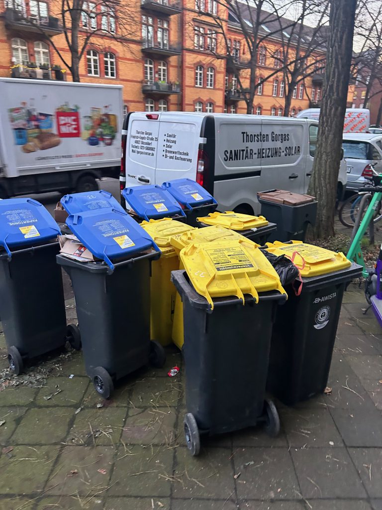 Volle Mülltonnen zur Abholung am Straßenrand bereitgestellt