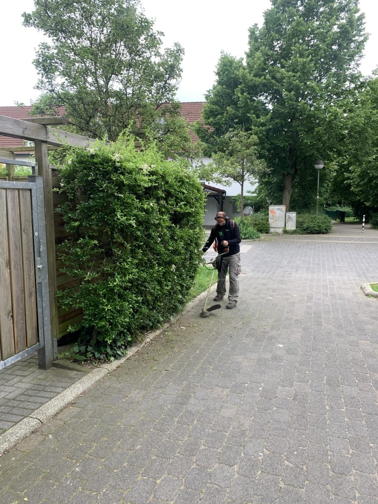 Mitarbeiter mit Freischneider bei der Grundstückspflege in Düsseldorf