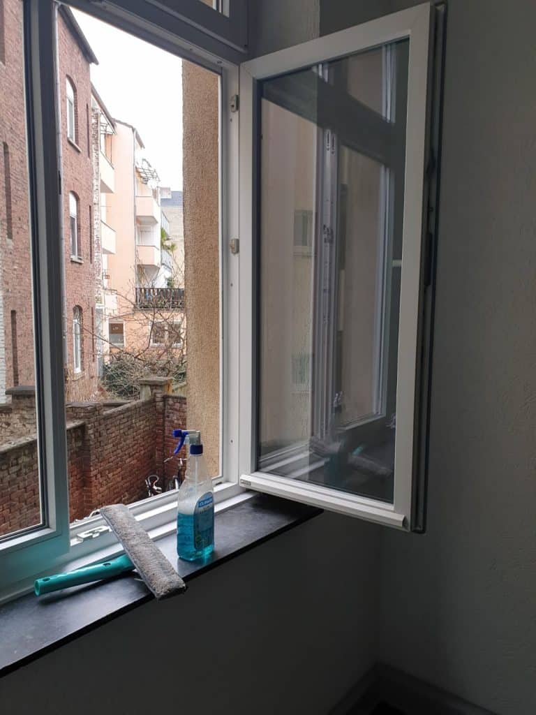 Reinigungsmittel auf einer Fensterbank vor geöffnetem Fenster